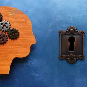 Silhouette di testa arancione con ingranaggi e serratura a forma di buco della chiave su sfondo blu, simbolo di autocritica e blocchi mentali.