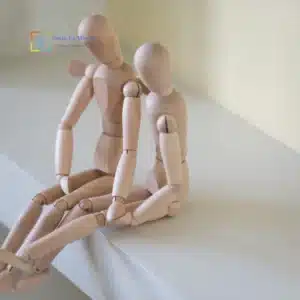 Due manichini di legno seduti vicini che simboleggiano empatia e supporto psicologico dopo una separazione.