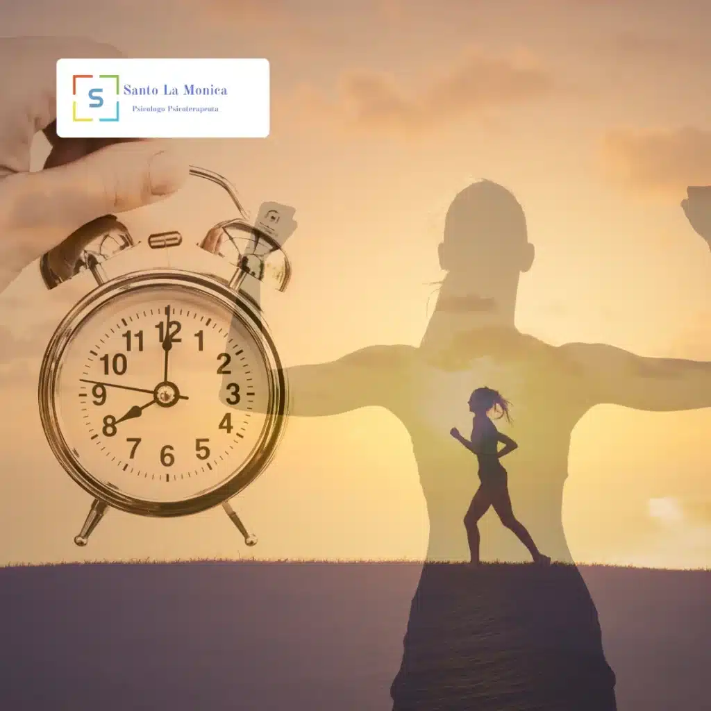 Sveglia in primo piano e silhouette di persona con braccia aperte al tramonto, simbolo di motivazione e cambiamento (logo Santo La Monica).