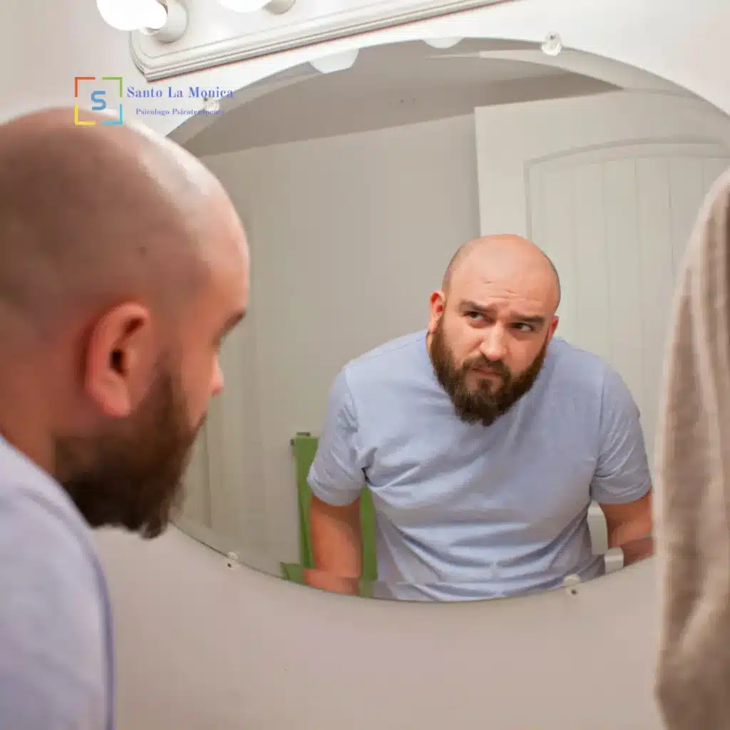 Uomo che si osserva allo specchio con espressione pensierosa, immagine sulla bassa autostima e l’insicurezza.
