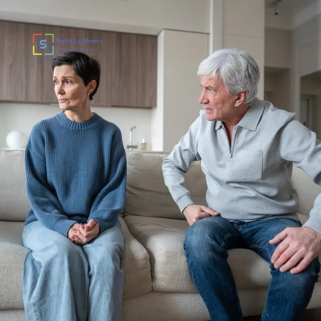 Coppia seduta sul divano durante un momento di tensione emotiva nella relazione.