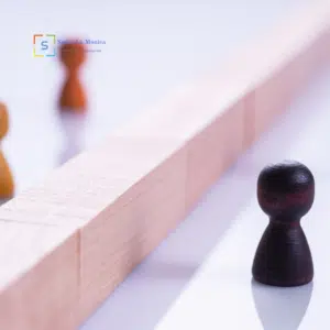 Pedine separate da una barriera di legno, simbolo di distanza emotiva e squilibrio relazionale.